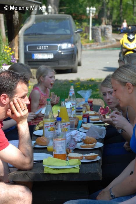 Gemeinsames Mittagessen an langen Tischen im Hof
